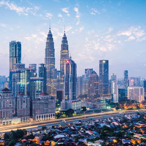 A shot of Kuala Lumpur Malaysia skyline at dusk featuring the iconic Petronas Twin Towers and Kuala Lumpur tower