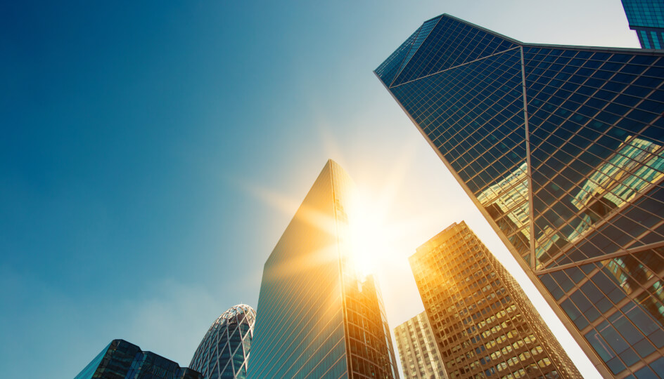 Skyscraper glass facades on a bright sunny day with sunbeams in the blue sky