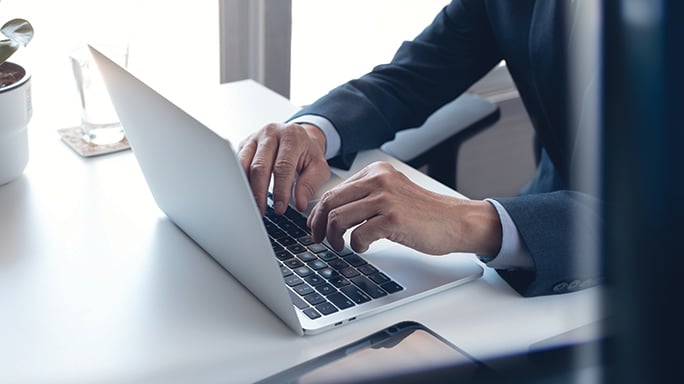 An individual in a suit engages with a laptop, illustrating the process of trade receivable securitization